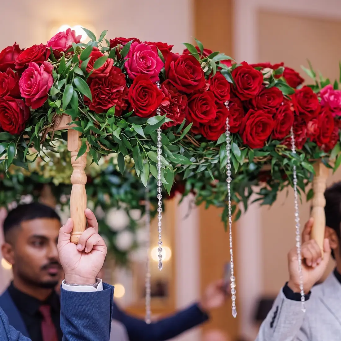 Close-up detail of The Royal Roses canopy: cascading red roses, lilac accents and eucalyptus greenery